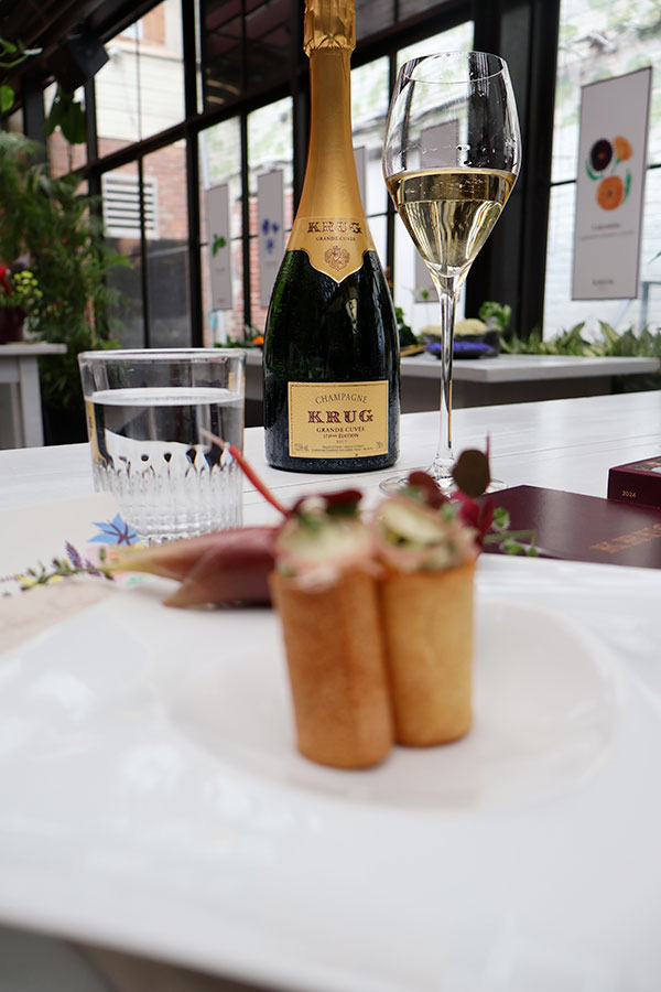 Le Tartare de kampachi à la fleur de gingembre, mayonnaise à l’oxalis pourpre, brunoise de concombre et avocat avec fleur de chrysanthème et une coupe de KRUG Grande Cuvée lors de la journée de presse de la KRUG Week 2024 à Montréal