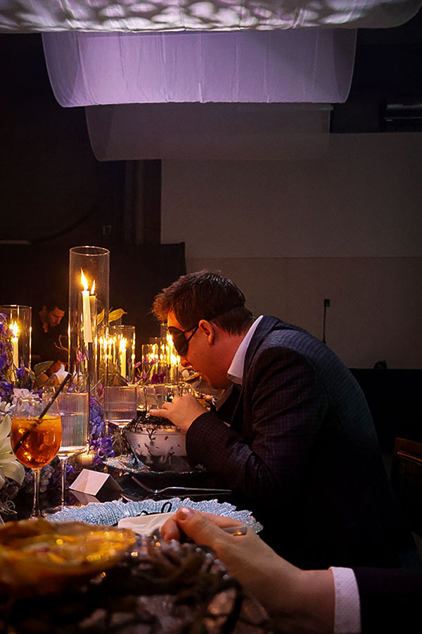 Un des invités tentant l'expérience de manger les yeux fermés à la Soirée Takumi Keiken par Lexus