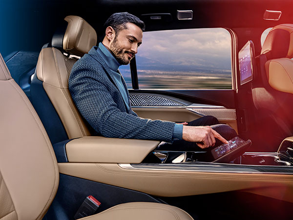Homme assis dans le fauteuil président à la deuxième rangée du Cadillac Escalade IQ 2025 utilisant l'écran de commande arrière.