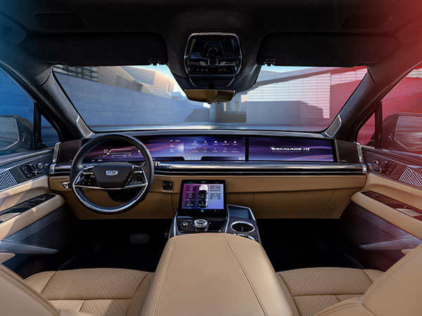 Vue orientée vers l'avant de l'intérieur du Cadillac Escalade IQ et de l'écran de 55 po d'un montant à l'autre à partir du siège arrière.